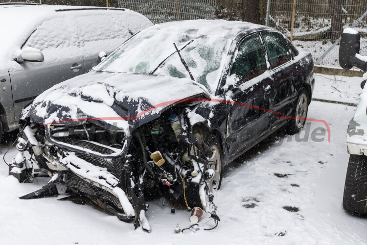 Ein beschädigtes Auto mit starkem Schaden am Vorderende steht im Schnee.